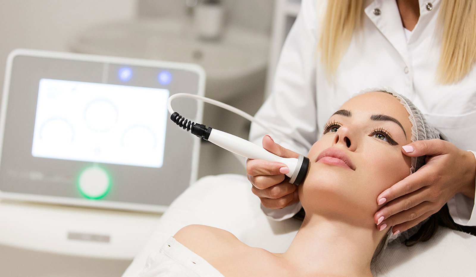 A clinician using an aesthetic treatment handpiece on a patient’s face